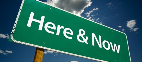 "Here & Now" Road Sign with dramatic clouds and sky.
