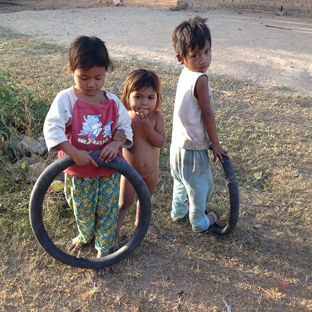 2/ Ảnh ba người con nhỏ của bố mẹ Trim, buổi chiều lấy lốp xe đạp làm xe chạy chơi trên con đường của Buôn Làng.