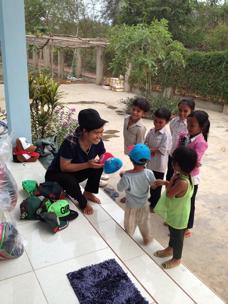 1/ Trong sân nhà các Yăh, Yăh phát mũ cho các em nhỏ trong Buôn Làng.