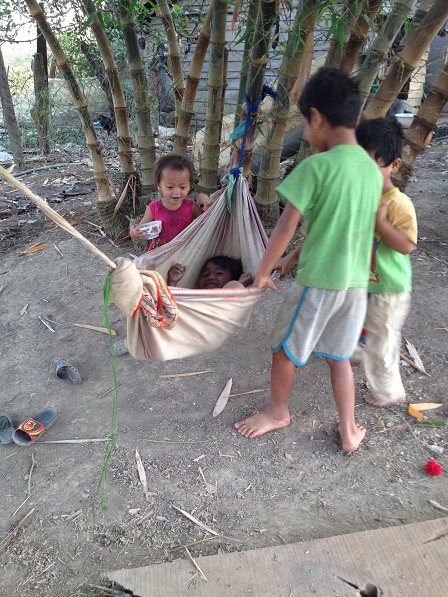 2/ Em nhỏ vừa bưng chén cơm ăn vừa chơi đùa với các anh.