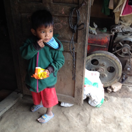 Ảnh em Xiêm hai tuổi đứng ăn Osin trước của nhà hàng xóm là nhà của bố mẹ E ở thôn Năm.