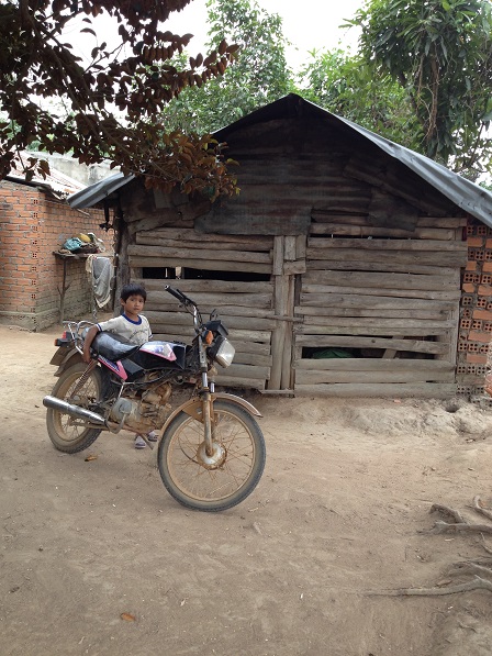 Ảnh em Số đứng trước sân nhà của gia đình.