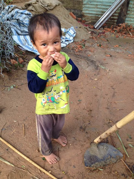 Em Gân đang ăn một khúc nhỏ bắp đỏ nướng trong sân phía sau nhà.