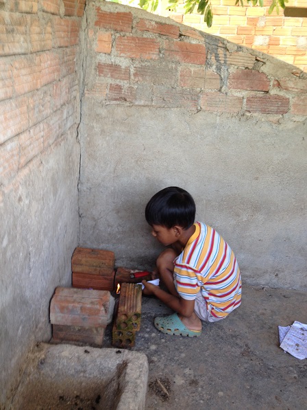 Người con trai út của mẹ Sâm đang một mình chơi đốt lửa trong góc nhà.