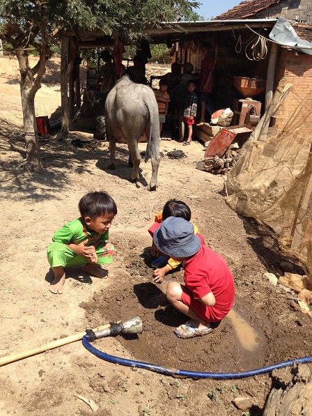 Ảnh ba người con nhỏ của bố mẹ Thiếu đang rất hạnh phúc, khi được chơi ngay chính vũng nước các em tự đào lên trong sân giữa trời trưa nắng _ Buôn Hằng