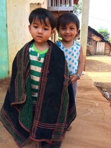 Hai em nhỏ ở sóc Bù Môn I đang chơi trước hiên nhà